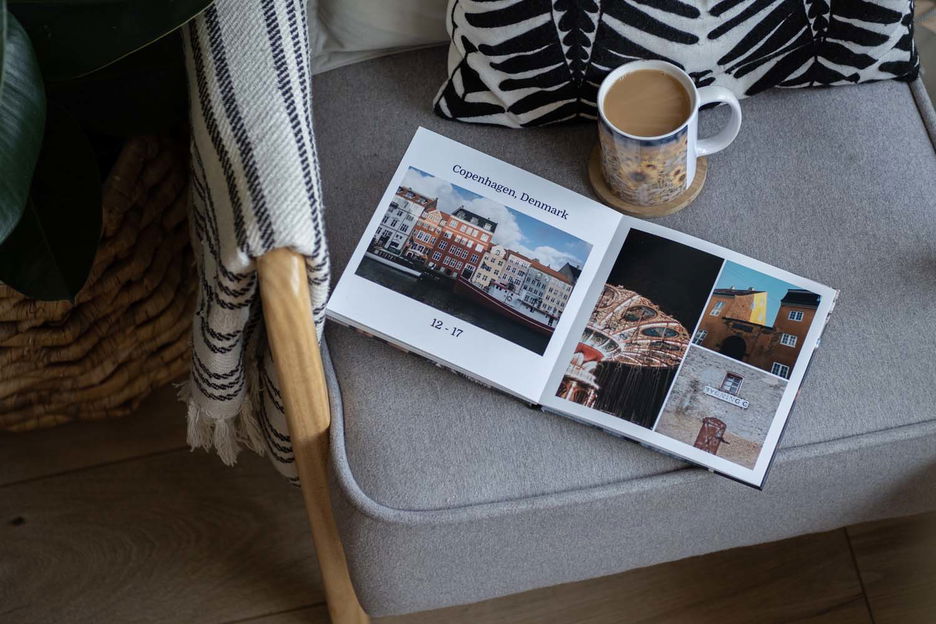 Photo book on chair with blanket and cup of coffee nearby