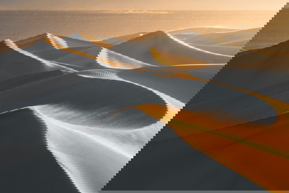 Row of sand dunes with flat desert behind