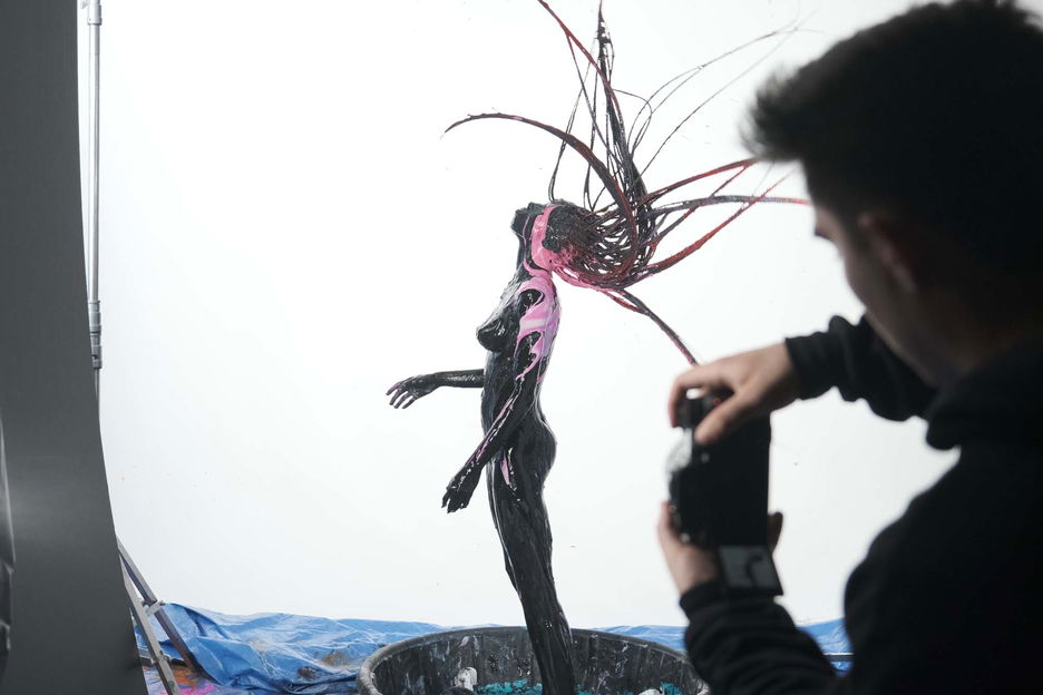 Soaked in various hues of paint, a woman tosses her braided hair in the air