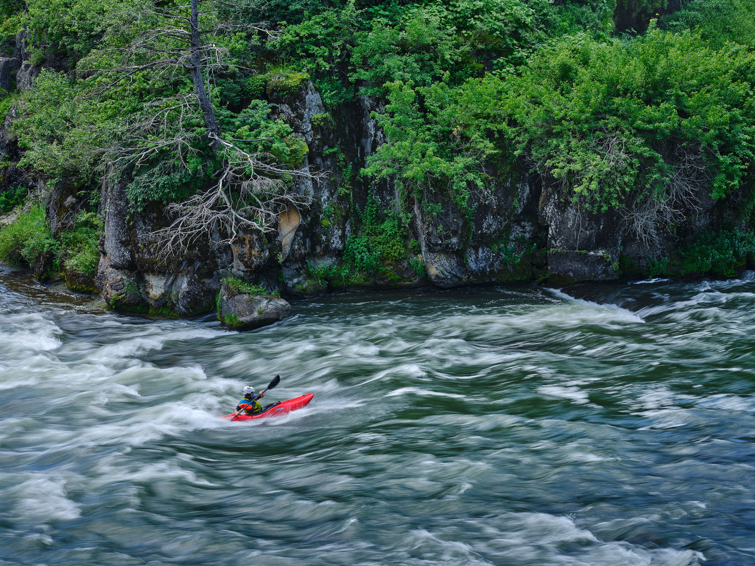 JT Hartman surfing a small standing wave while whitewater kayaking on the Henry's Fork River in Idaho.