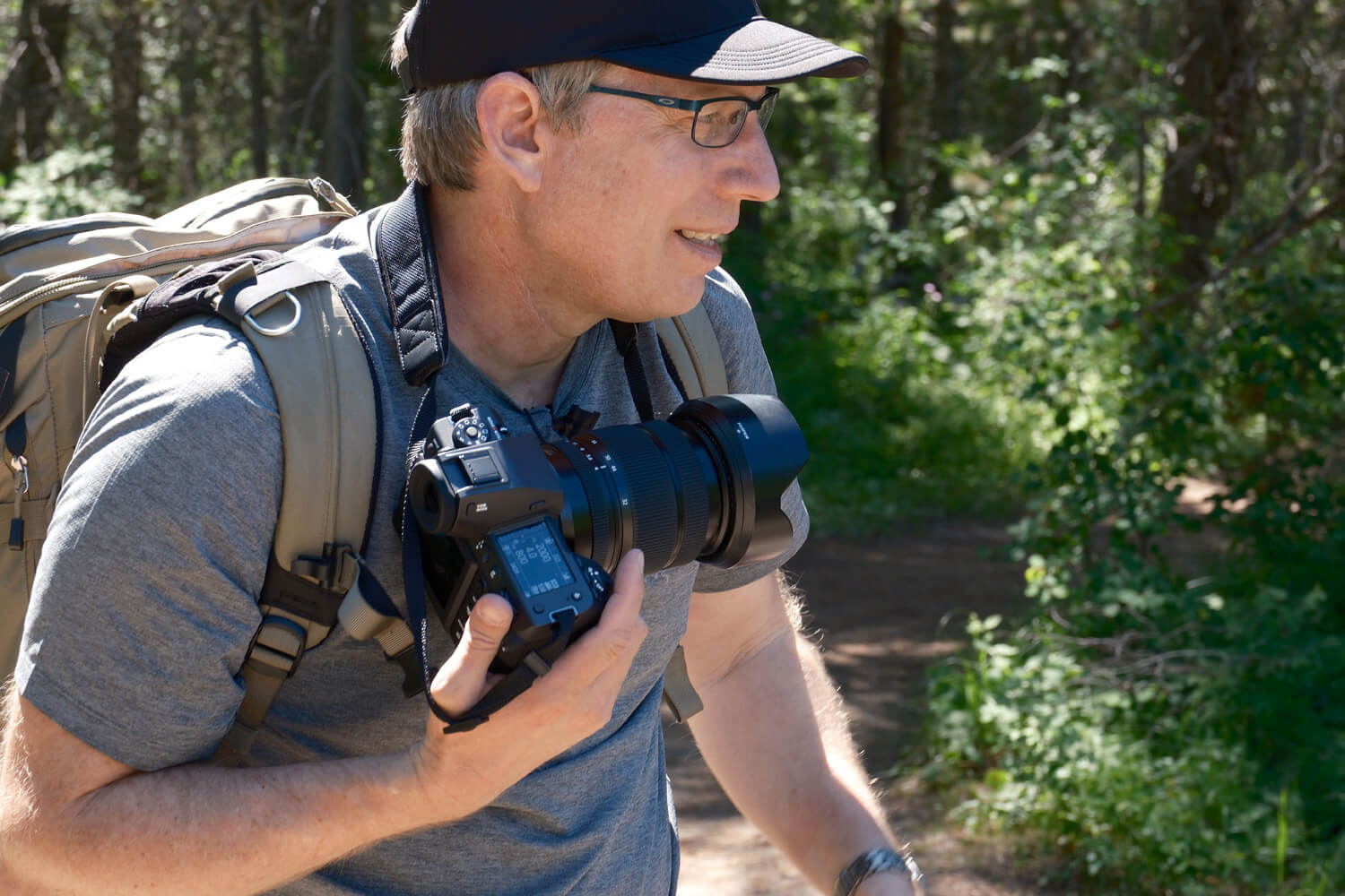 Action photographer Michael Clark holds GFX camera as he walks with back pack on