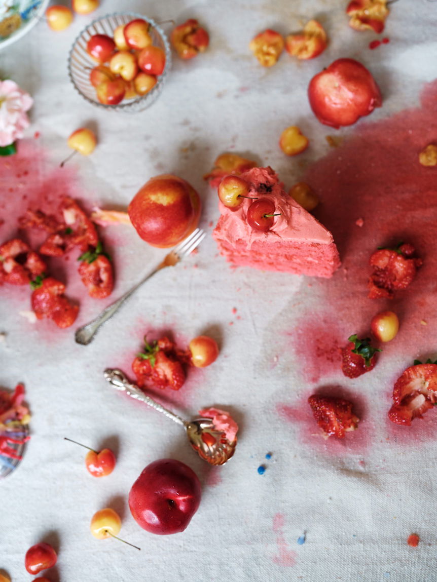 Flat lay of table cloth covered in spilt cake and squashed fruit that has stained the white table cloth red