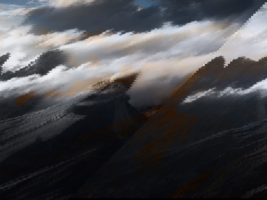 Clouds billowing over sun-kissed mountain peaks