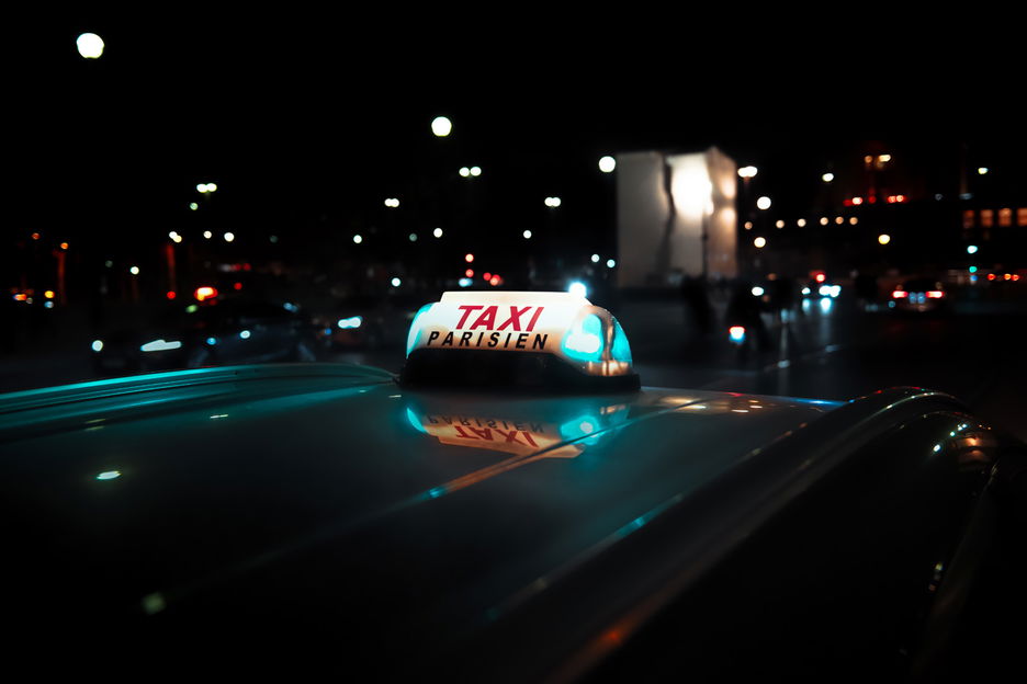 Lit sign of a Paris taxi on street at night