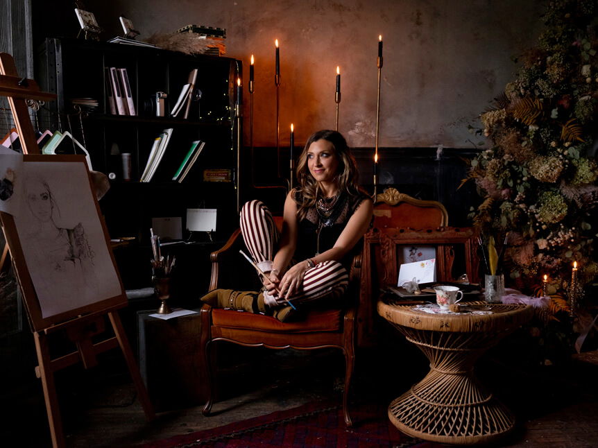 Professional photographer, Alison Conklin, on why the FUJIFILM GFX system is so good for location portrait photography. Interior environmental portrait of a woman sitting on an armchair in front of a book case in a candlelit room