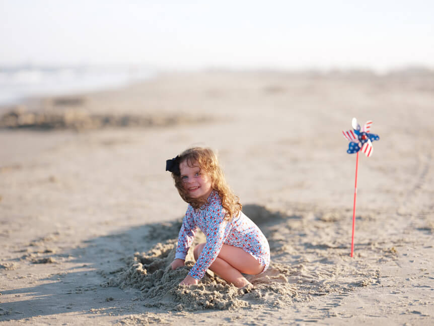 Professional photographer, Alison Conklin, on why the FUJIFILM GFX system is so good for location portrait photography. Image of a young girl building a sand castle on a beach.