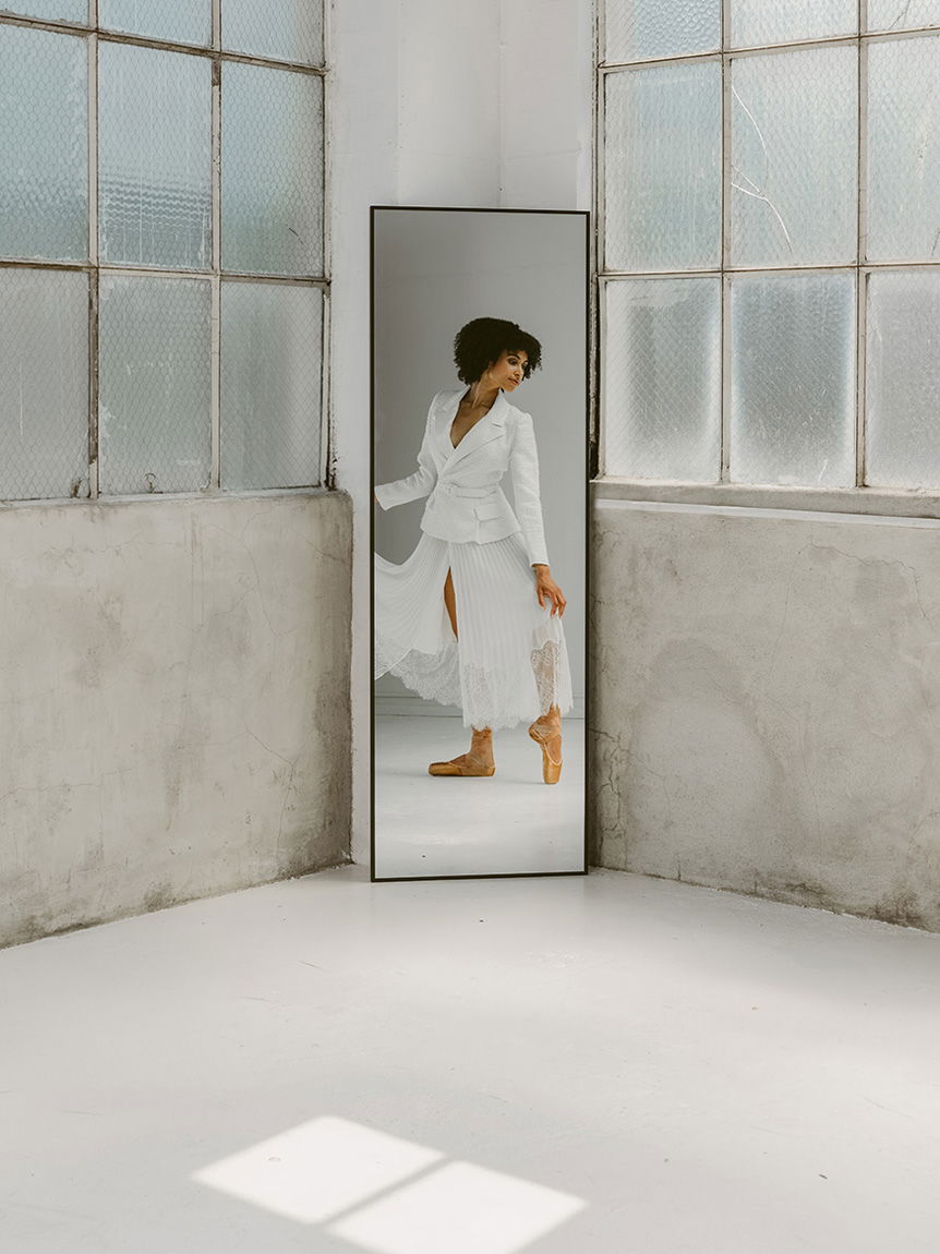Young, dark-haired woman doing ballet in front of mirror
