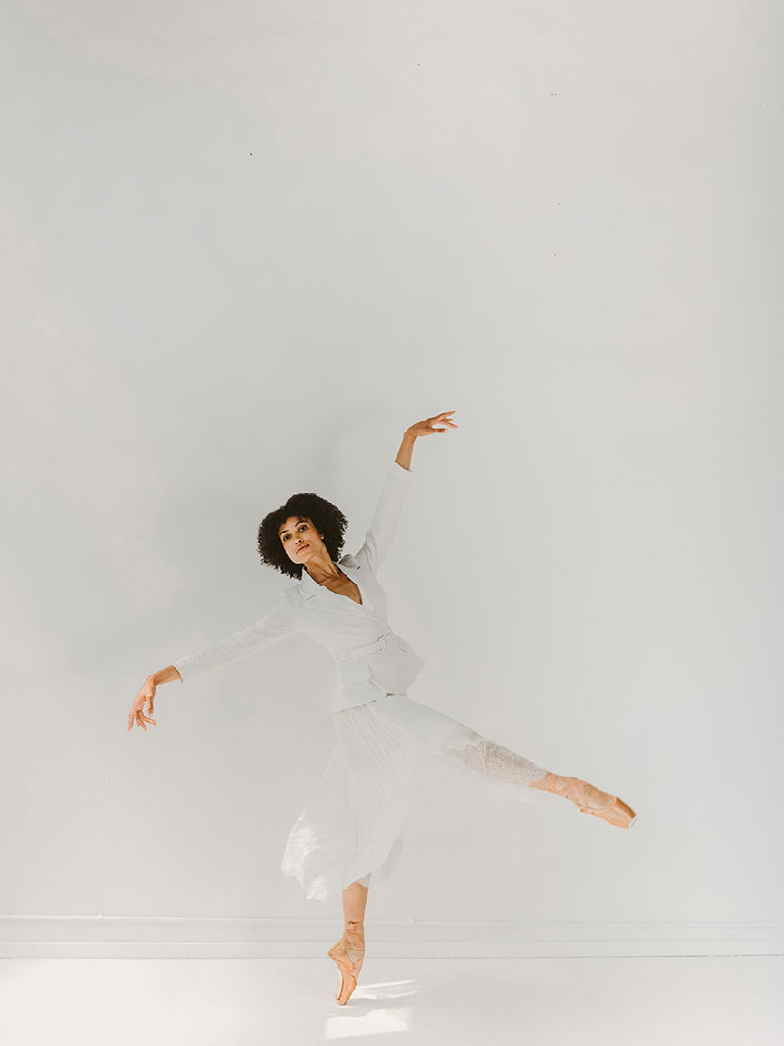Young, dark-haired woman doing ballet in empty, white room