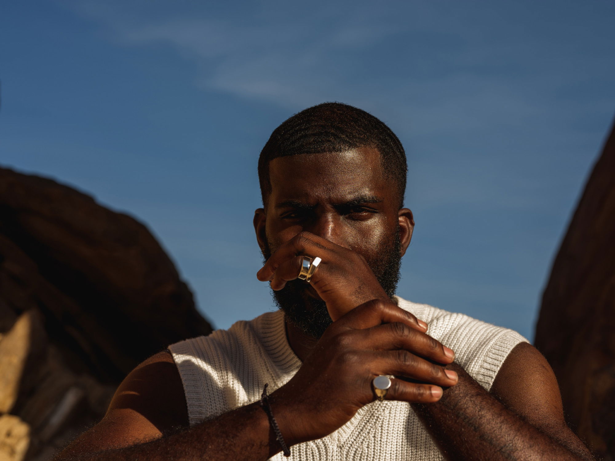 An African-American man stares at the camera, framed against the bluish bokeh of the sky