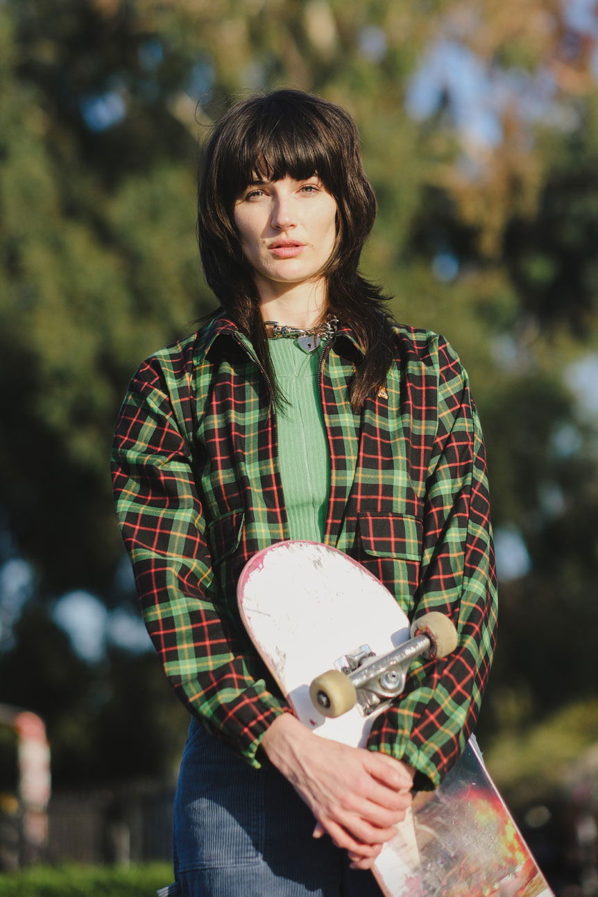 Young woman in plaid shirt holding skateboard
