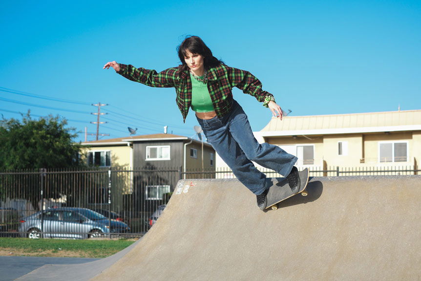 Young woman skateboarding on small ramp in skatepark
