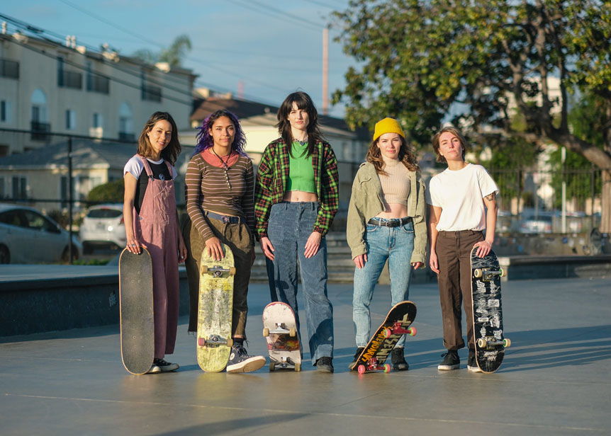 Group of young women skateboarders posing in skatepark