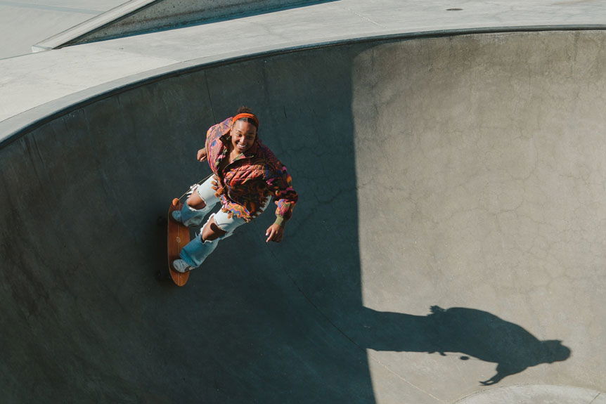 Woman skateboarding in concrete skatepark bowl
