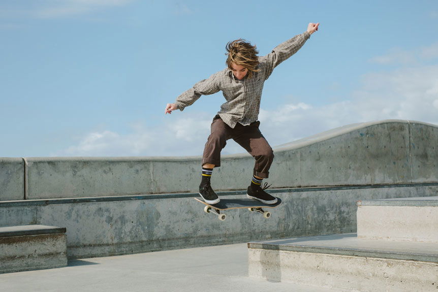 Young woman skateboarder performing ollie down concrete stair inside California skatepark