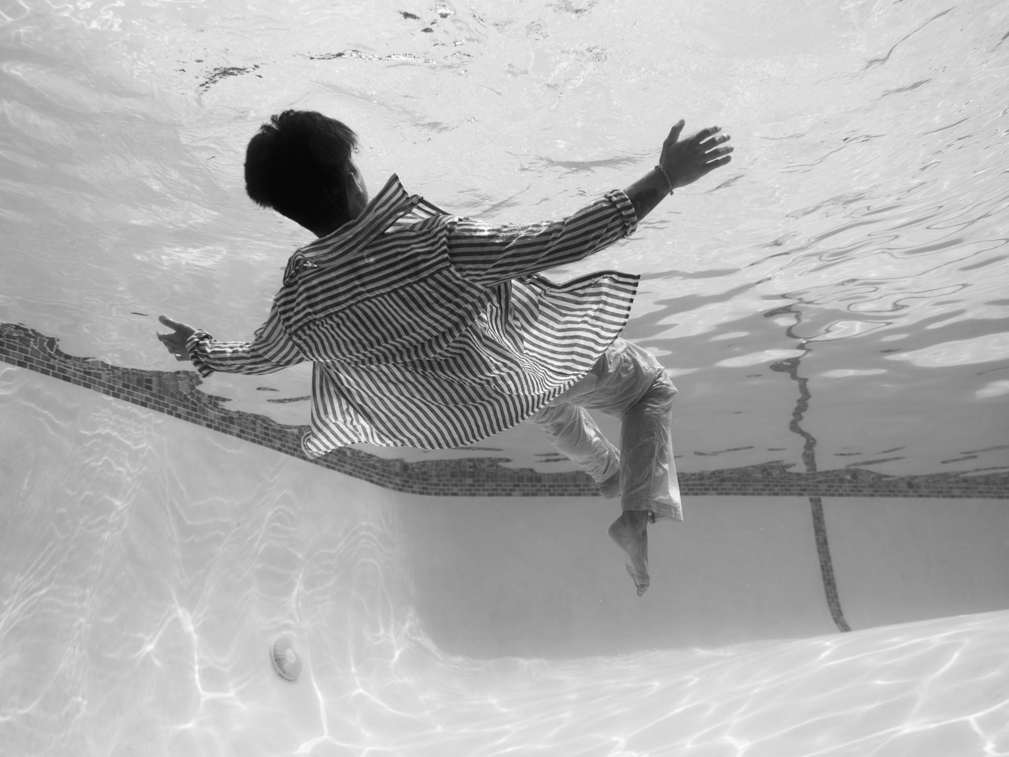 A black and white picture depicts a man, floating in a submerged space of stark contrasts