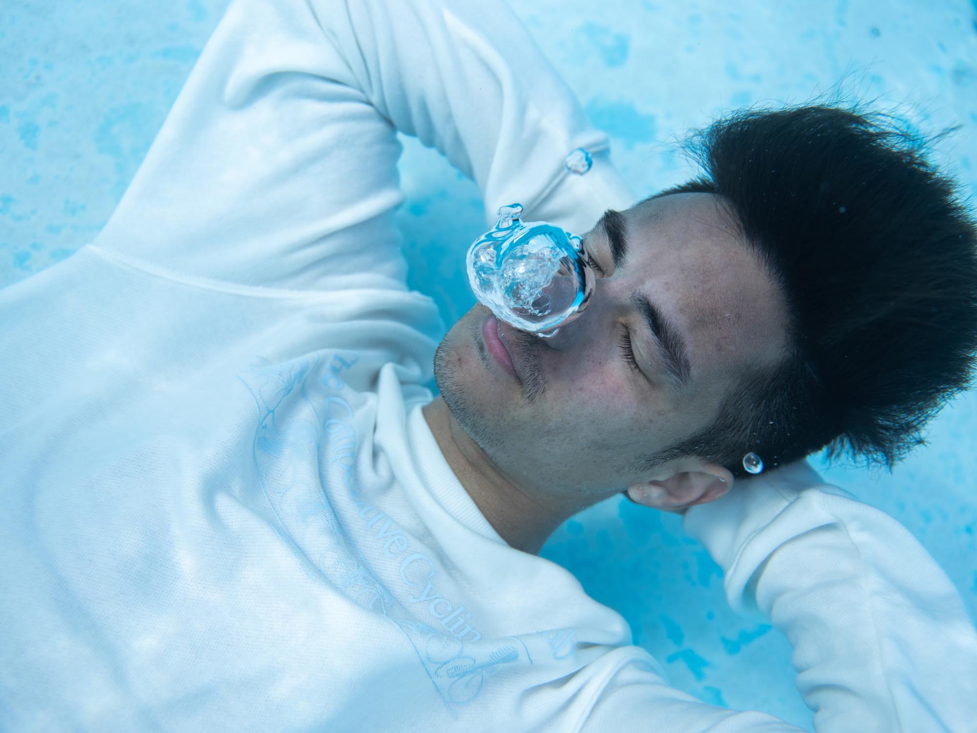 A man relaxes underwater, stretching his arms