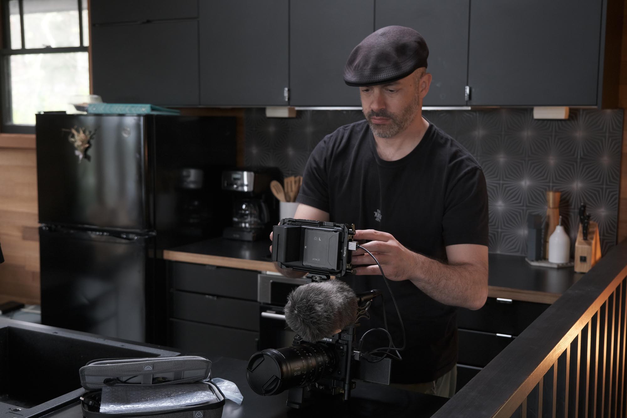 A man in a hat adjusts a camera rig
