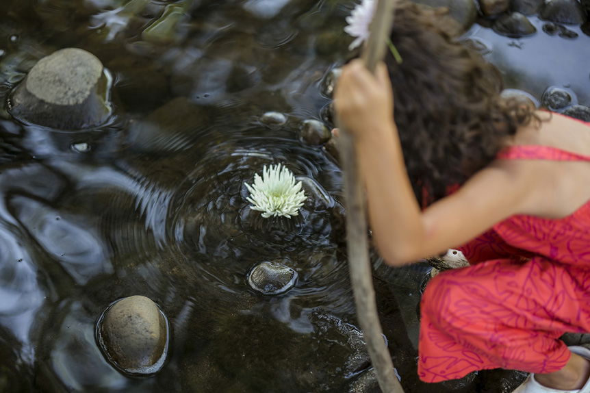 Young girl observing large, white flower in calm stream
