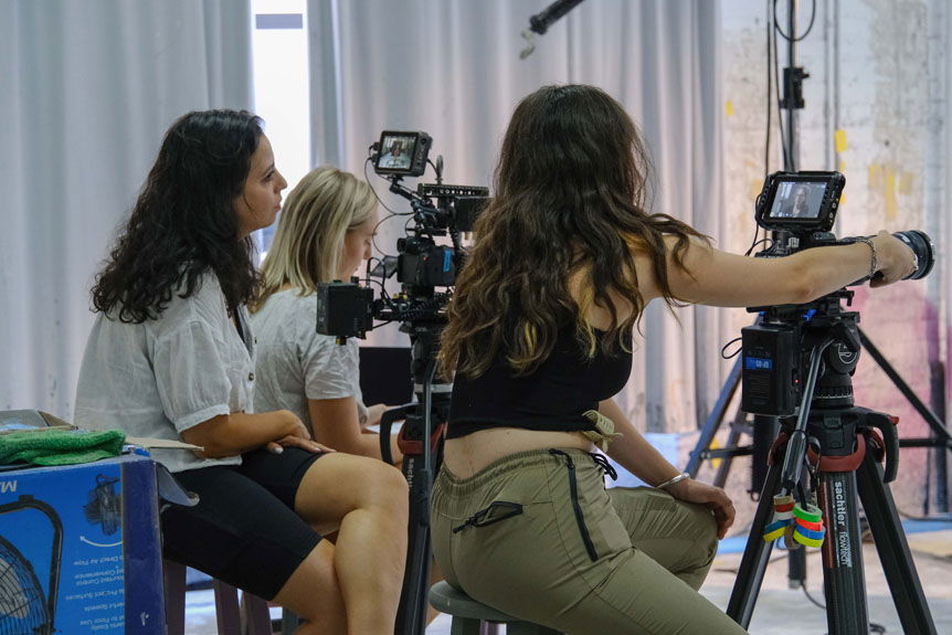 Three women filming behind cameras in art studio