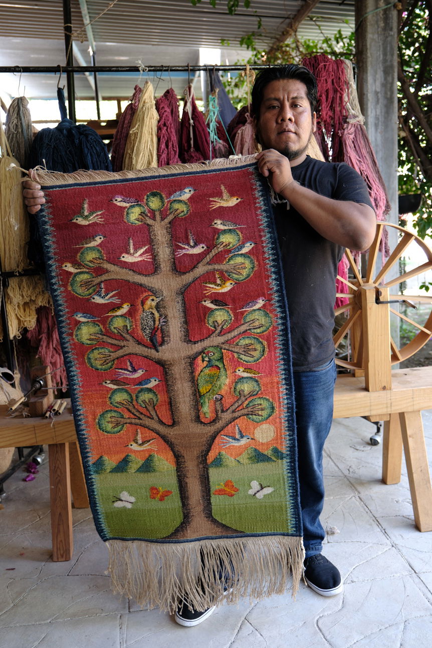 Oaxacan man holding traditional woven rug