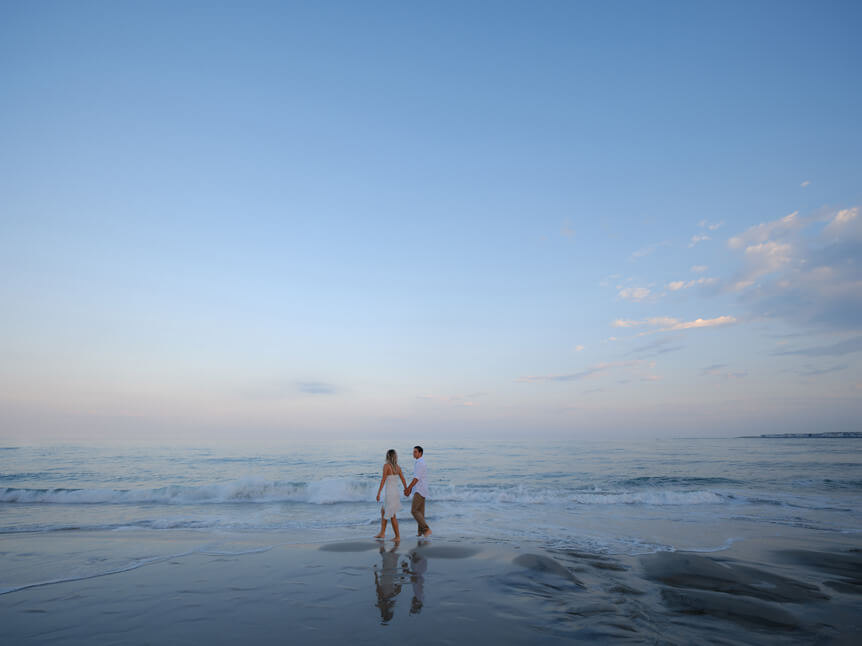 Wide shot of couple walking on beach.