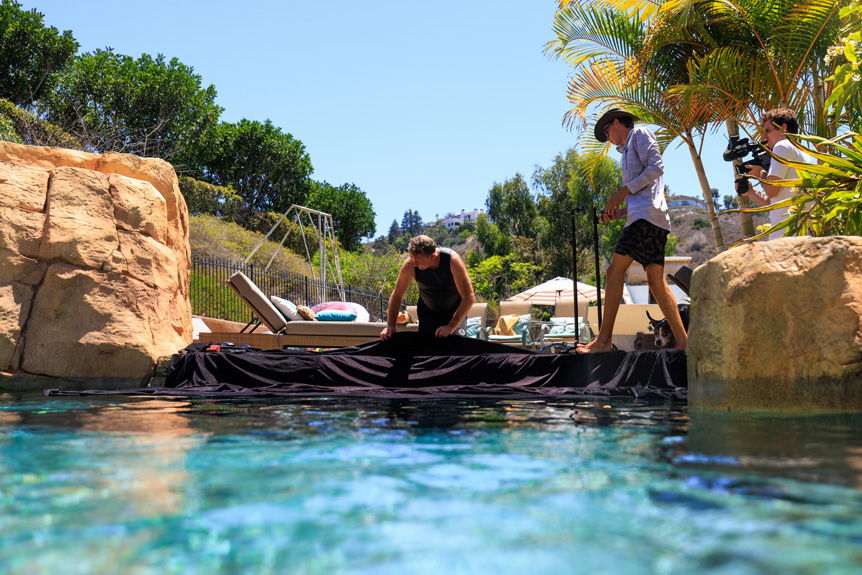 Two men assembling photography backdrop by poolside