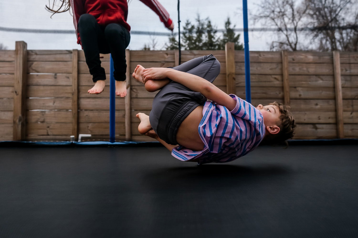 Boy in mid air bouncing on a trampoline while in the foetal position