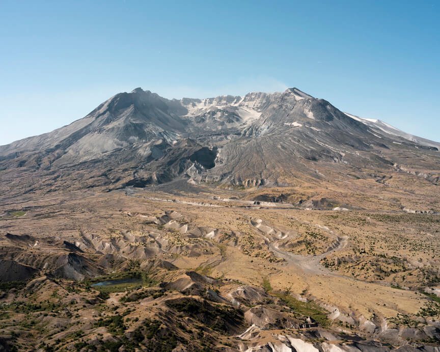 Rugged brown landscape leading to wide volcano