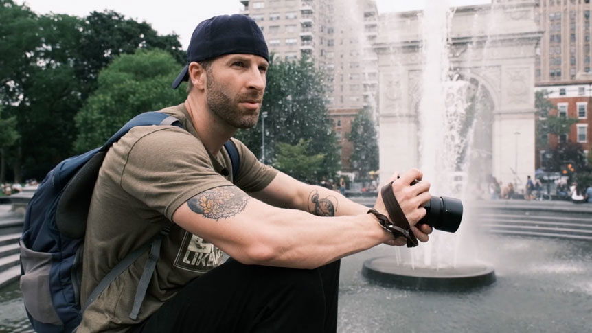 Tattooed street photographer sat on edge of fountain