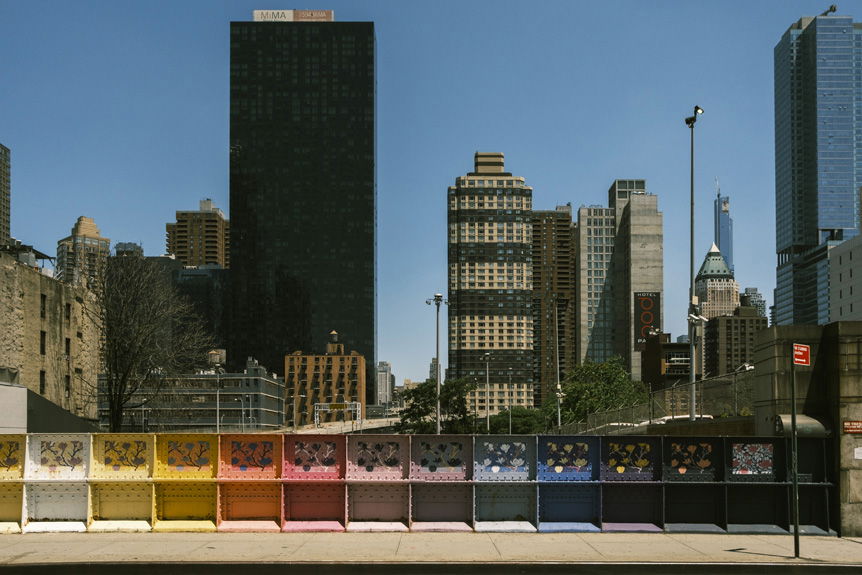 Rainbow-painted guard rail with New York City skyline beyond