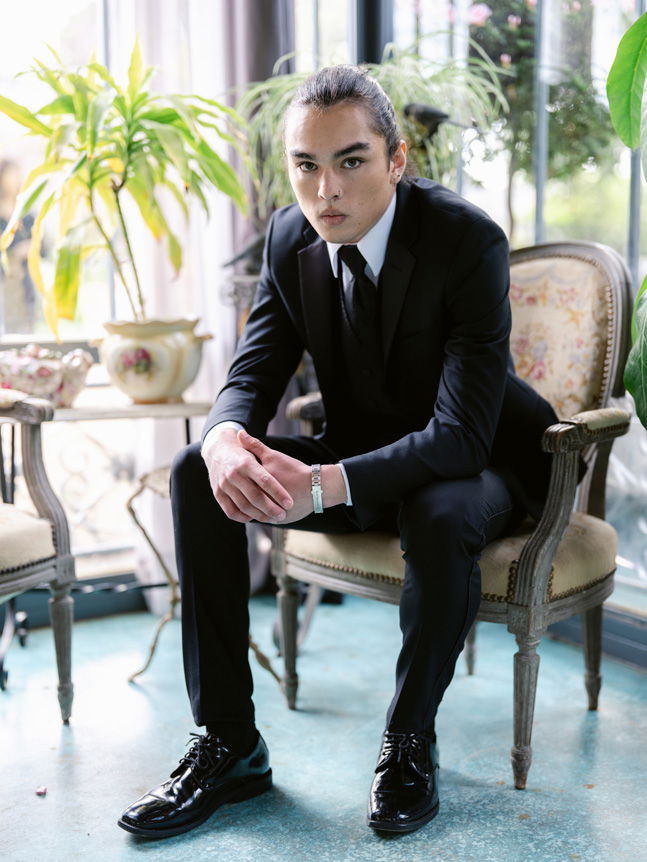 Groom sat in chair wearing wedding suit