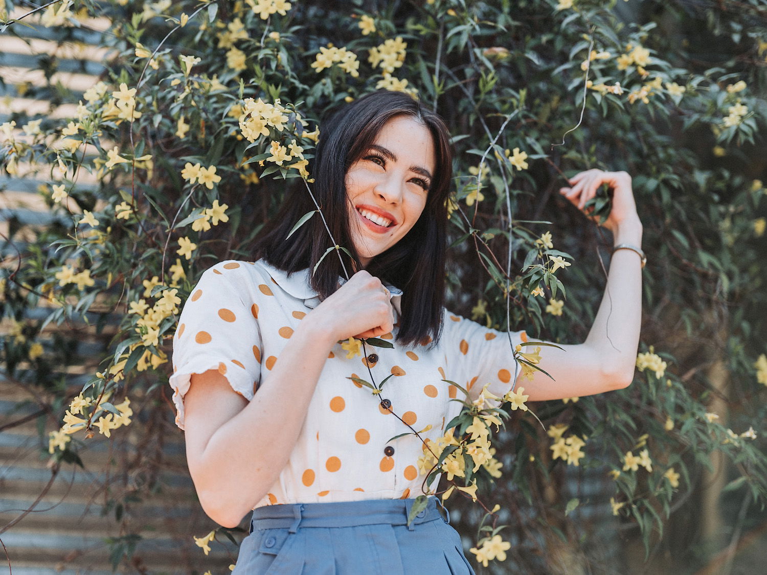 Women posing and smiling in front of green plant with yellow flowers