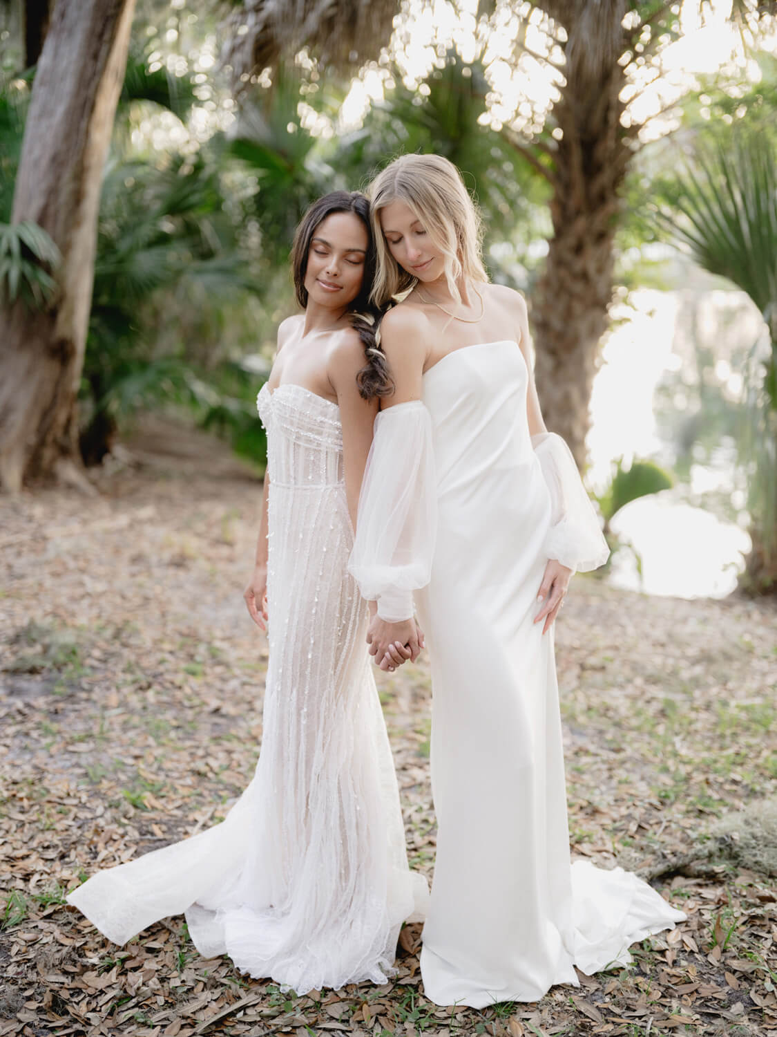 Brides in white dresses posing and walking together in forest setting