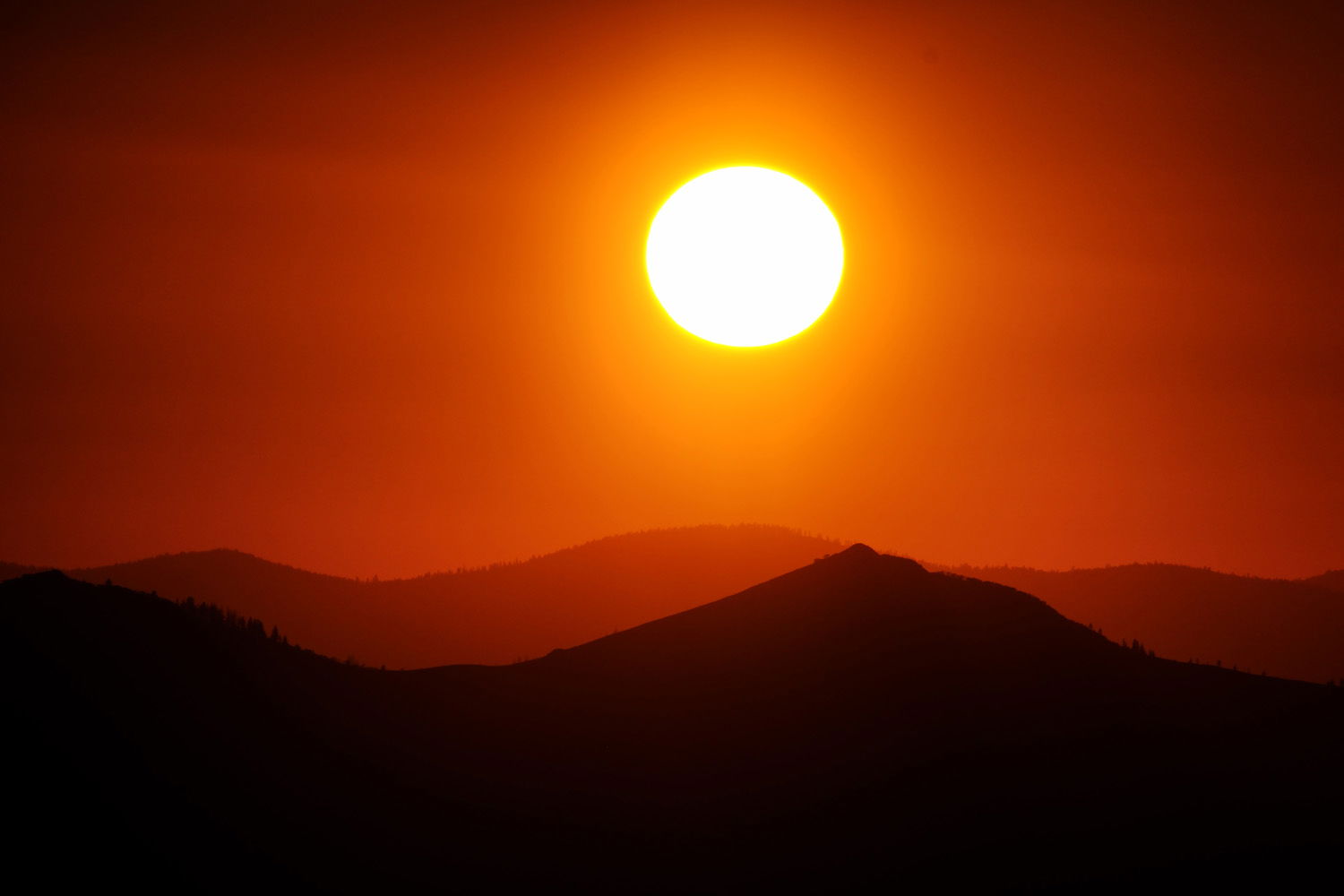sun in the sky over mountains at sunset