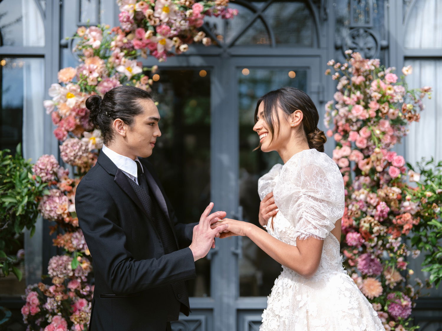 bride and groom at wedding with backdrop of flowers