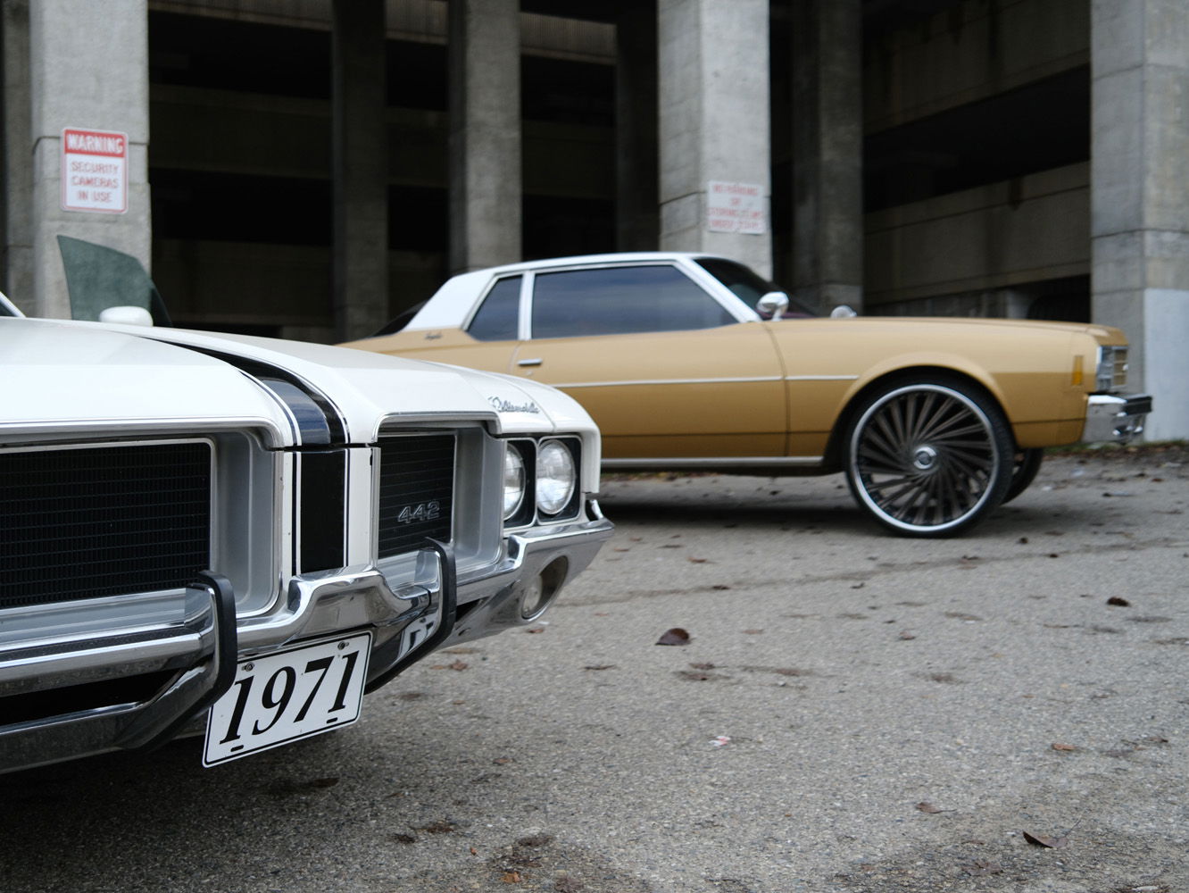 two classic cars in a concrete parking lot