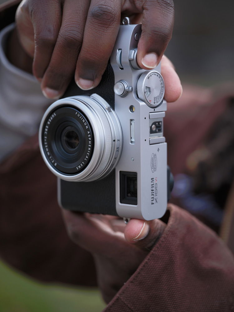 Close up of someone holding X100VI fixed lens premium compact camera and making an image.