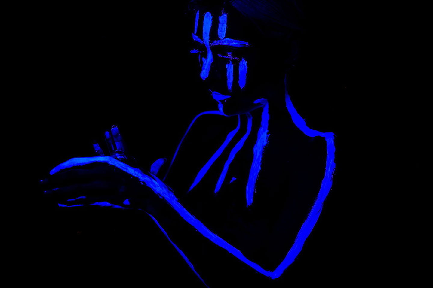 Frau mit UV-Farbe geschminkt im Schwarzlicht