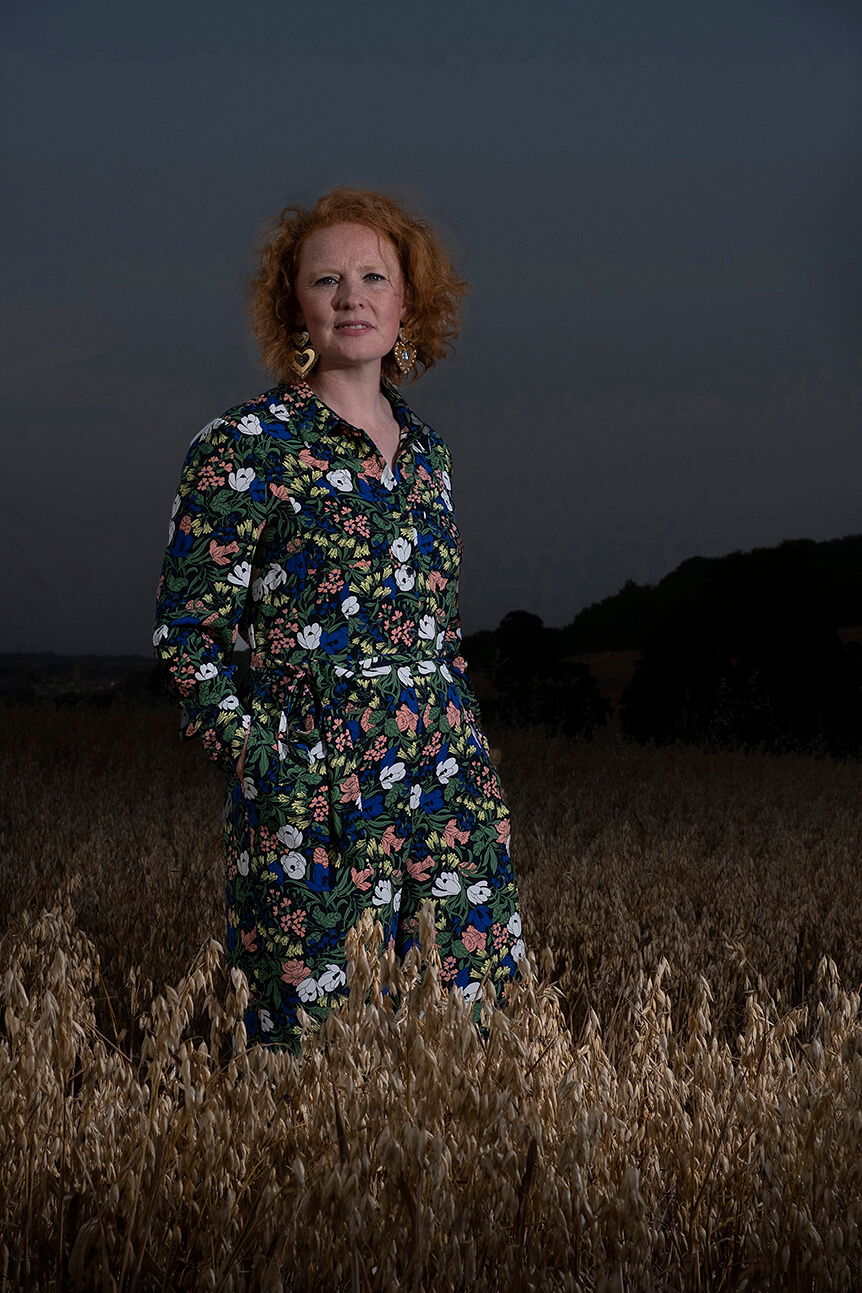 Red-haired woman in a wheat field at dusk with flash