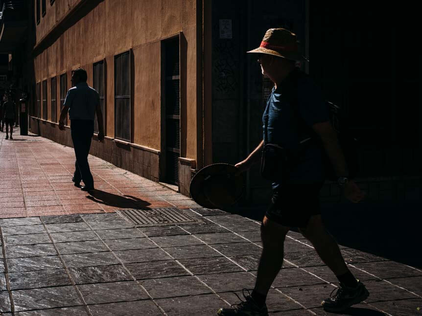 Man walking down a shadowy street in the evening